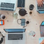 People collaborating around laptops in an open office representing the era of corporate blogging