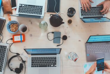 People collaborating around laptops in an open office representing the era of corporate blogging