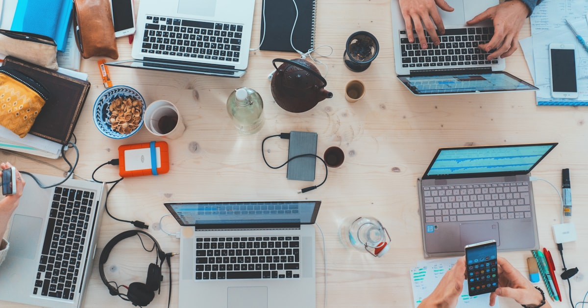 People collaborating around laptops in an open office representing the era of corporate blogging