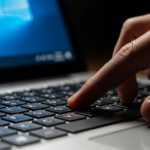 Hand pressing the F2 key on a laptop keyboard to open BIOS