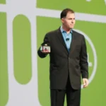 Michael Dell standing on stage at Oracle OpenWorld in front of large Android logos