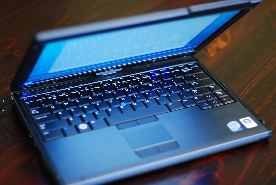 A Dell Latitude XT2 convertible laptop open on a wooden table